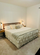 Zinus wood platform bed with slatted headboard in a minimalist bedroom, styled with white ruffled bedding and accent pillows, highlighting sturdy mattress support, timeless design, and a cozy, uncluttered sleep space with warm bedside lighting