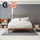 Modern bedroom with wood bed frame and neutral bedding against gray wall, styled with bookshelves, pillows, and woven basket; badges include AD Best Sleep Winner 2024 and Real Homes So Chic Awards Winner, highlighting recognition for sleep comfort and design.
