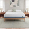 Zinus Balanced Comfort Core Hybrid Mattress fully set up on a natural wood platform bed frame in a light, airy bedroom with white and green pillows, nightstands, and lamps on either side, showing the mattress in its intended home bedroom setting.