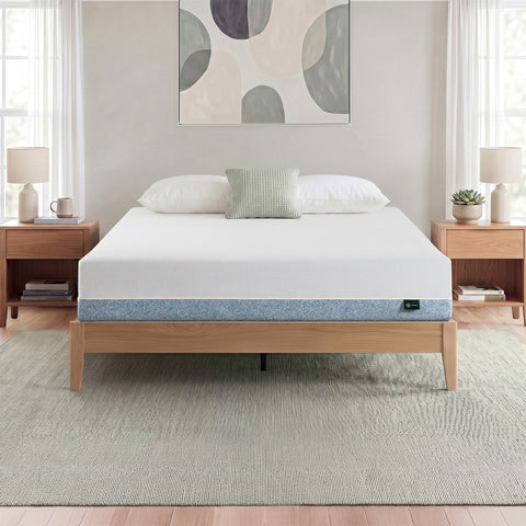 Zinus Balanced Comfort Core Memory Foam Mattress fully set up on a natural wood platform bed frame in a light, airy bedroom with white and green pillows, nightstands, and lamps on either side, showing the mattress in its intended home bedroom setting.