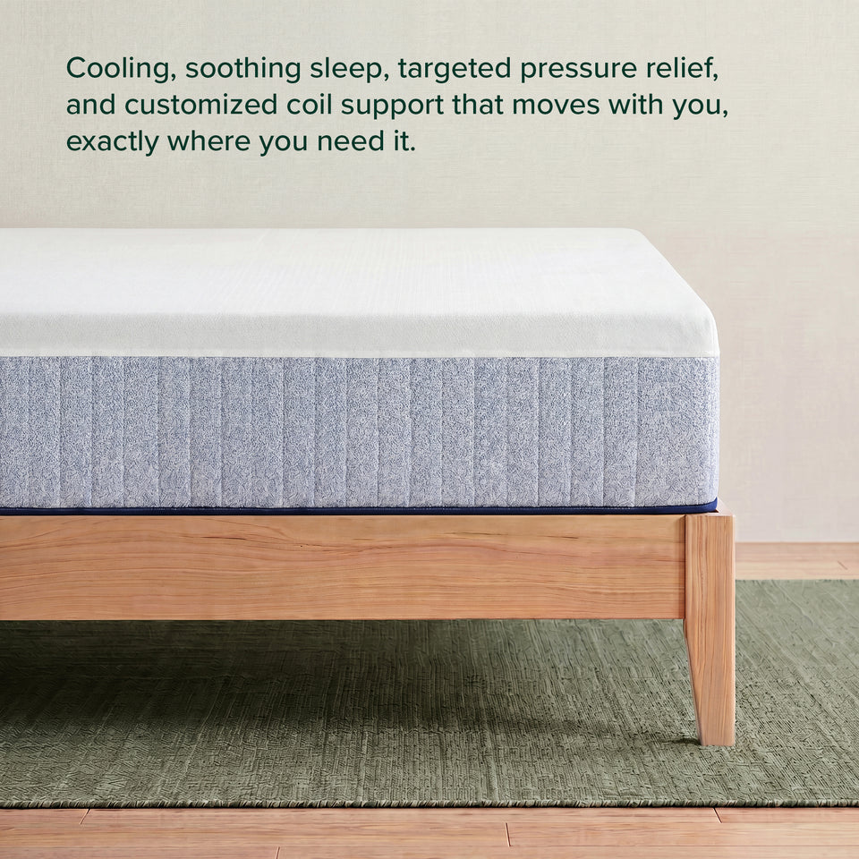 Zinus Balanced Comfort Signature Hybrid Mattress, side view close-up of the white knit cover and channel-quilted gray woven base on a natural wood platform frame, with on-image text reading: 'Cooling, soothing sleep, targeted pressure relief, and customized coil support.