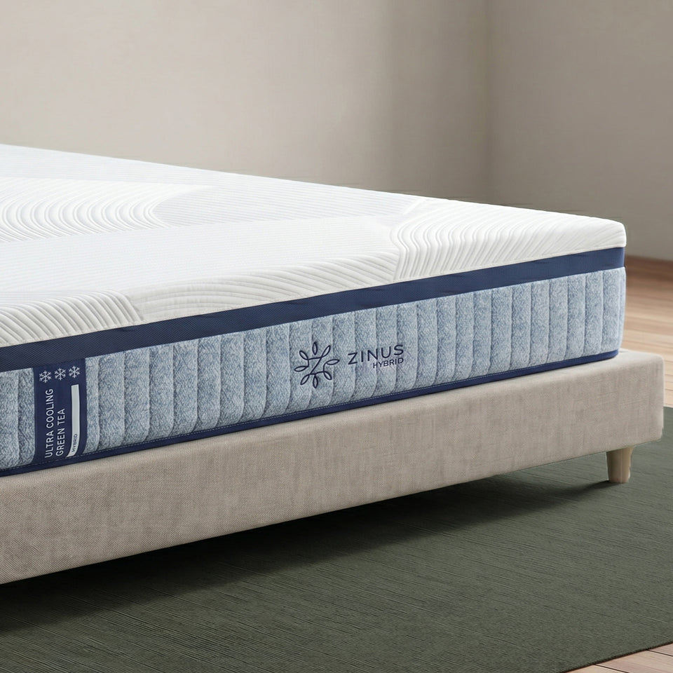 Zinus Ultra Cooling Green Tea Hybrid Mattress, Queen, close-up corner detail on upholstered bed frame showing quilted white cover, ribbed blue side panel, snowflake icons, and Zinus Hybrid logo.