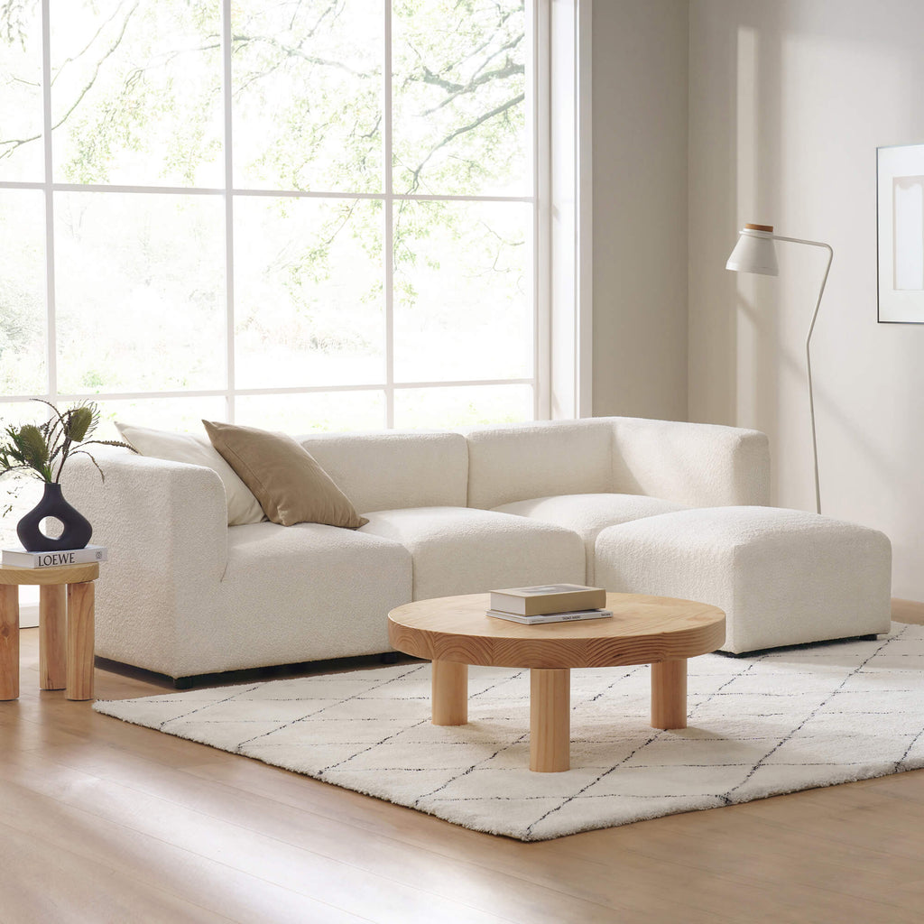 Zinus Luca Reversible Chaise Sectional Sofa in ivory boucle fabric styled in a bright living room with large windows. Sectional features modern curves and plush seats, paired with wood coffee table, rug, and accent pillow, emphasizing versatile comfort for contemporary homes 