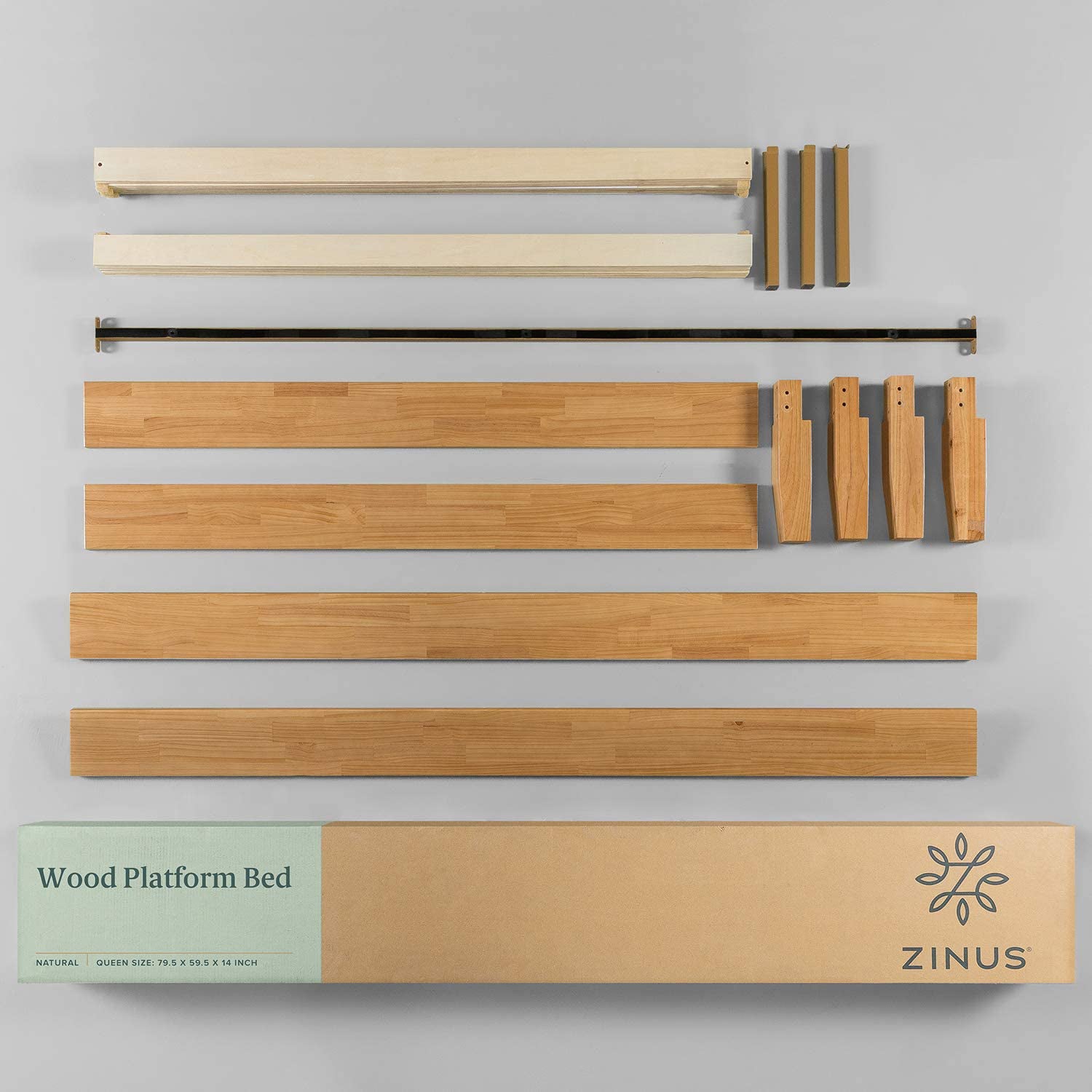 Unassembled Zinus wooden platform bed parts arranged, including side rails, tapered legs, support pieces, and hardware, shown with shipping box labeled 'Wood Platform Bed' in queen size natural finish.