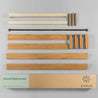 Unassembled Zinus wooden platform bed parts arranged, including side rails, tapered legs, support pieces, and hardware, shown with shipping box labeled 'Wood Platform Bed' in queen size natural finish.