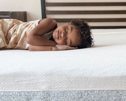 A young child sleeping on a Zinus Original Green Tea Memory Foam Mattress, which features a responsive comfort layer and green tea-infused memory foam for restful sleep.