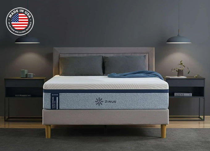 Zinus Ultra Cooling mattress on upholstered platform bed with gray headboard and bedding, styled in a modern dark-toned bedroom with pendant lamps, twin nightstands, and 'Made in USA' badge.