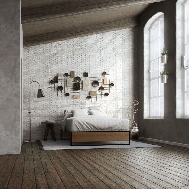 Zinus Suzanne Metal and Bamboo Platform Bed Frame styled in a loft bedroom with white brick walls. Black steel frame with bamboo accents and wood slats creates a modern industrial look, supporting a neatly dressed bed with white bedding.