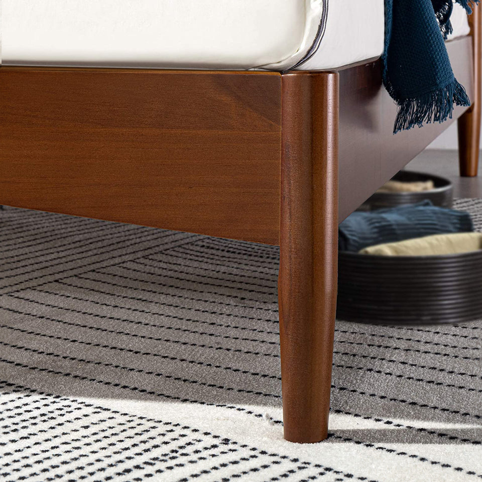 Close-up of Zinus Linda Wood Platform Bed Frame leg in rich walnut finish. Sturdy tapered wood leg supports sleek side rail with clean mid-century lines. Platform design offers lasting mattress support while providing underbed clearance for storage and modern bedroom style.
